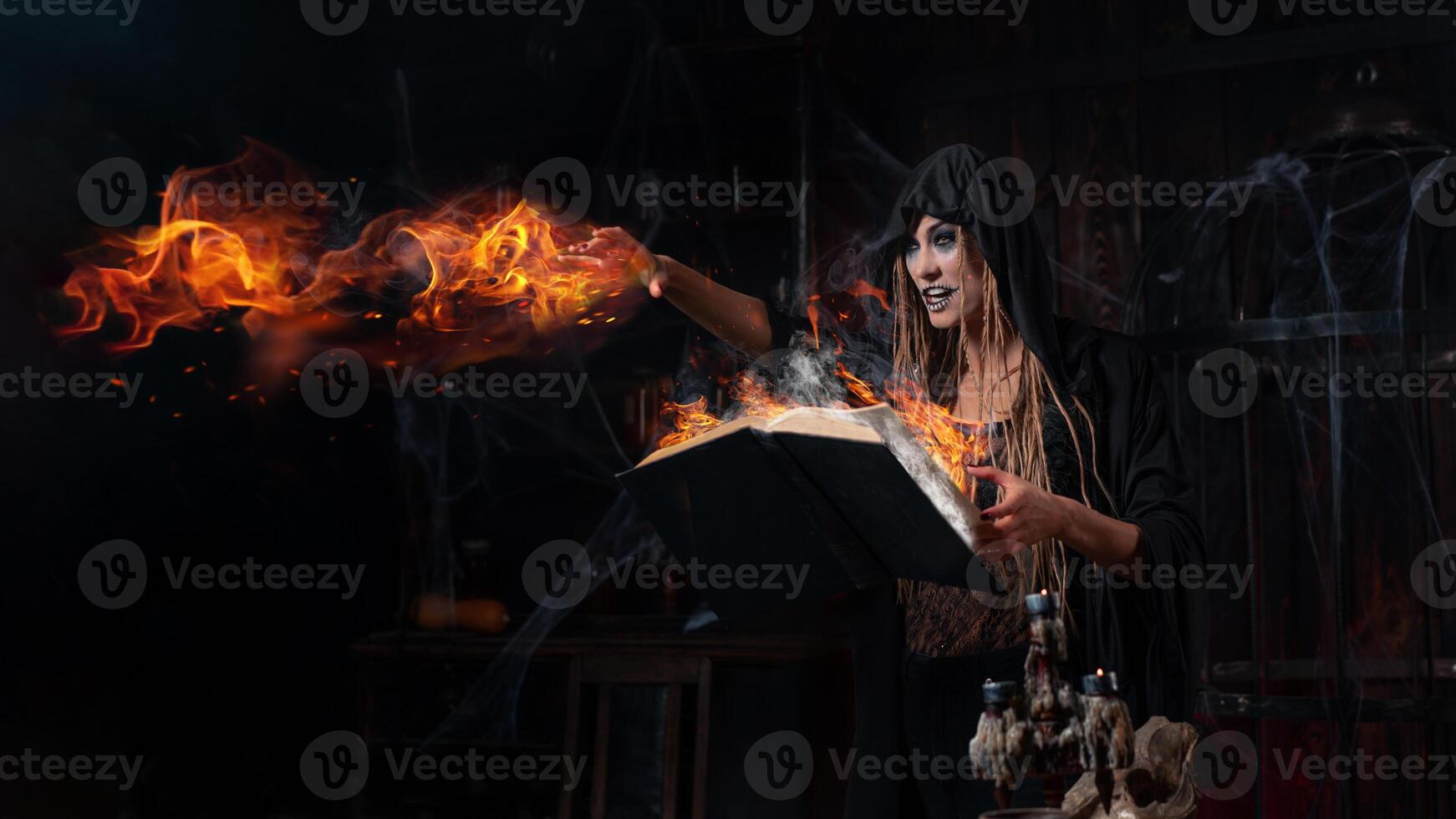 halloween concept. heks gekleed zwart kap met dreadlocks staand donker kerker kamer gebruik magie boek voor toveren magie spellen foto