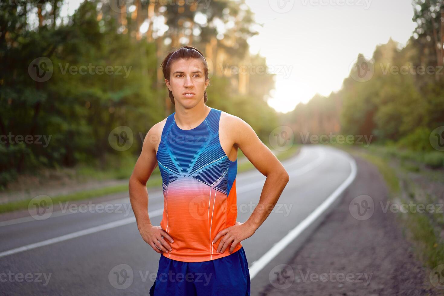 jong gekruld blond Kaukasisch Mens staand Aan asfalt Woud weg op zoek Bij camera voordat joggen. foto