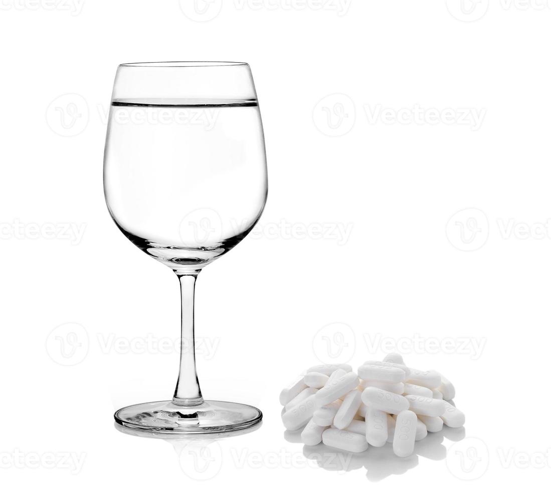glas water en pillen capsules geïsoleerd op een witte achtergrond foto