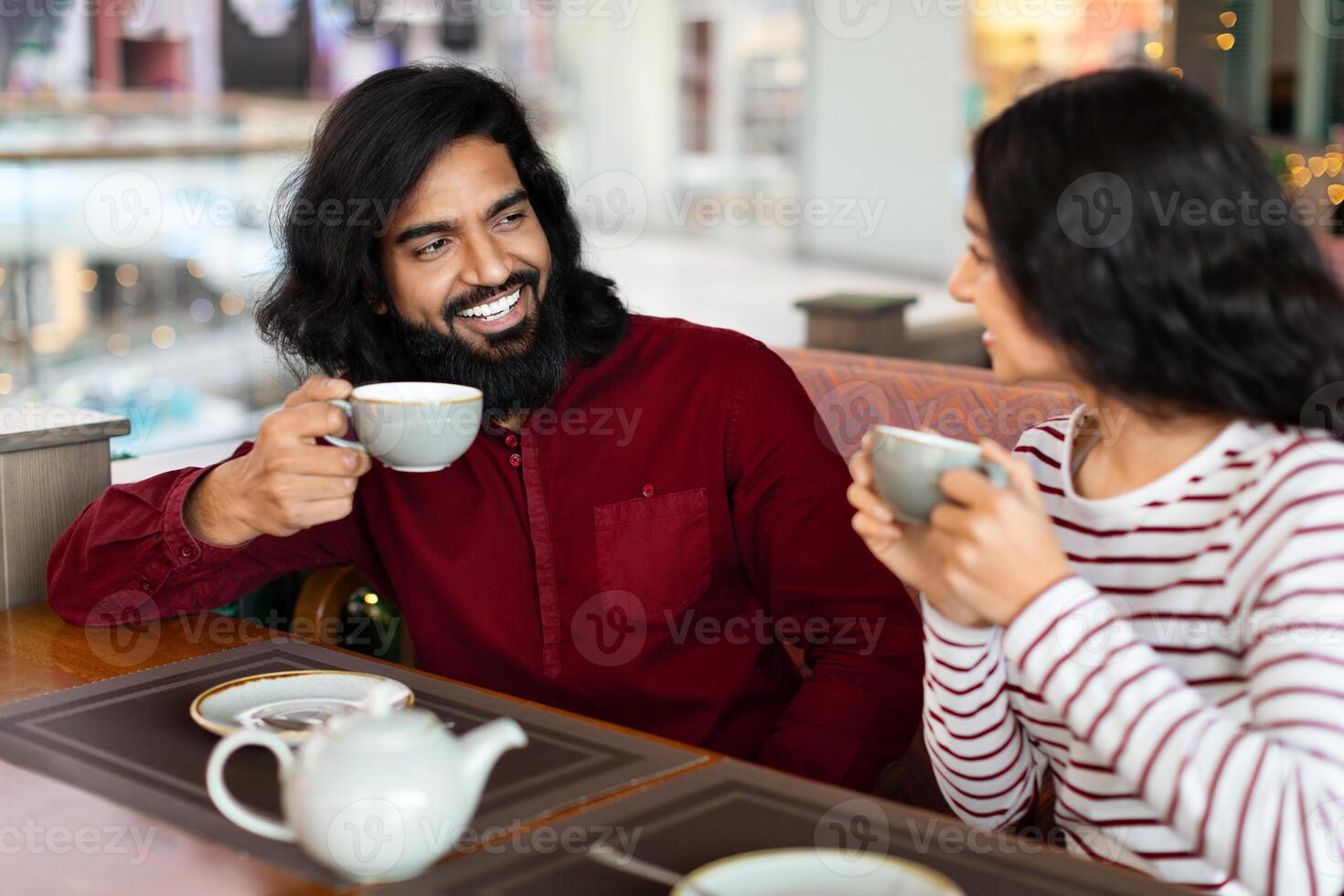 schattig aanhankelijk Indisch paar zittend Bij tafel in stad cafe foto