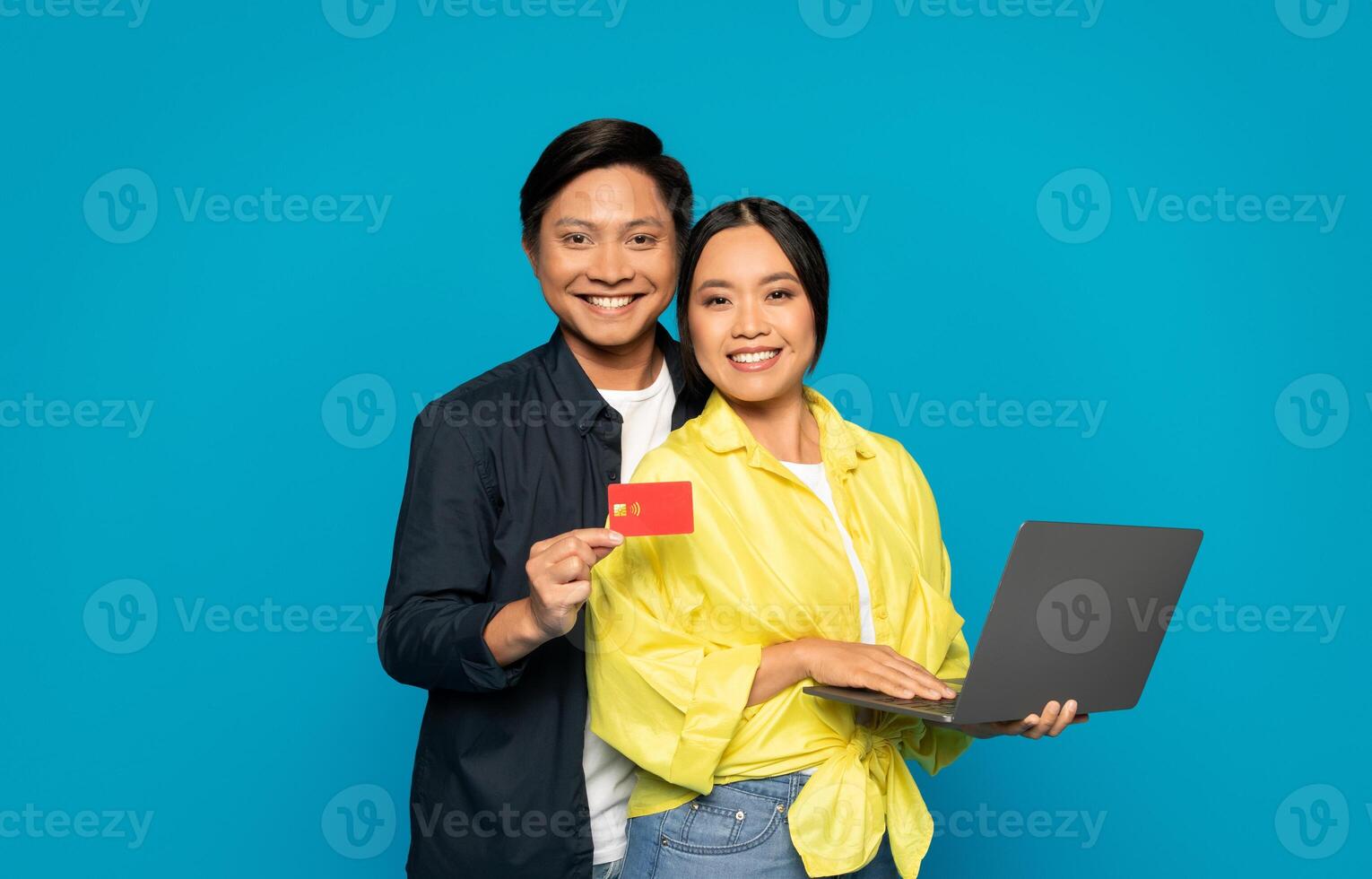 zelfverzekerd Aziatisch paar met laptop en credit kaart klaar voor online boodschappen doen foto