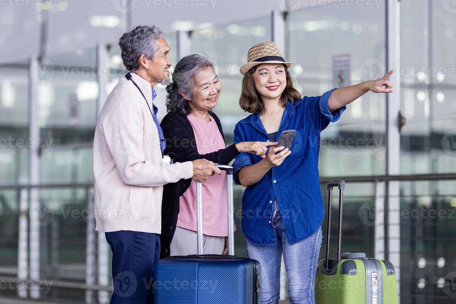 groep van Aziatisch familie toerist passagier met senior is gebruik makend van mobiel toepassing naar telefoontje plukken omhoog taxi Bij luchthaven terminal voor vervoer gedurende hun vakantie reizen en lang weekend vakantie foto