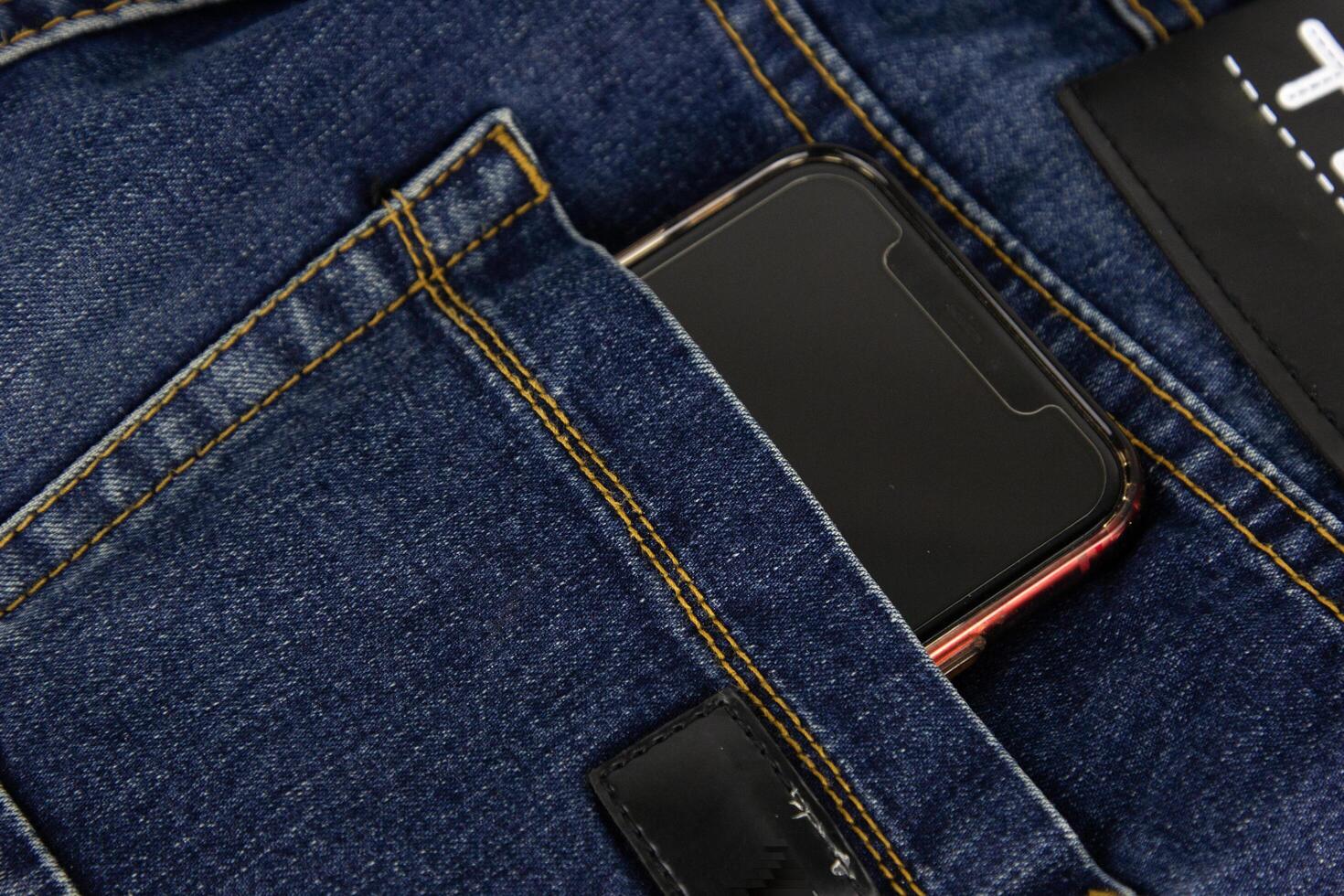 een blauw jeans zak- met mobiel telefoon in rood foto