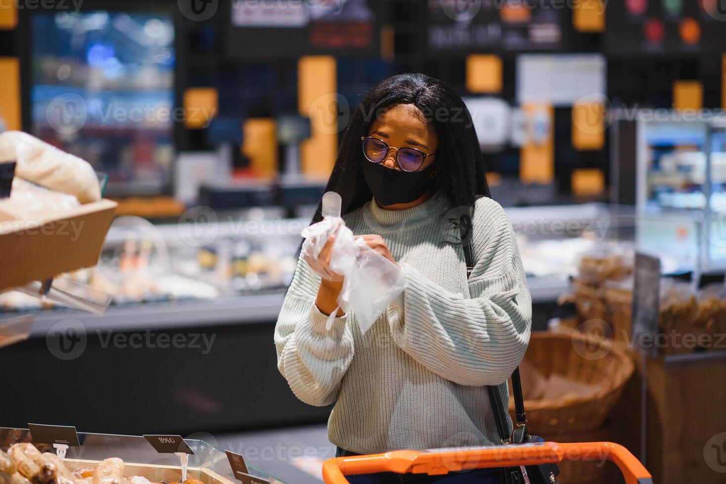 Afrikaanse vrouw vervelend beschikbaar medisch masker boodschappen doen in supermarkt gedurende coronavirus pandemia uitbraak. epidemie tijd foto