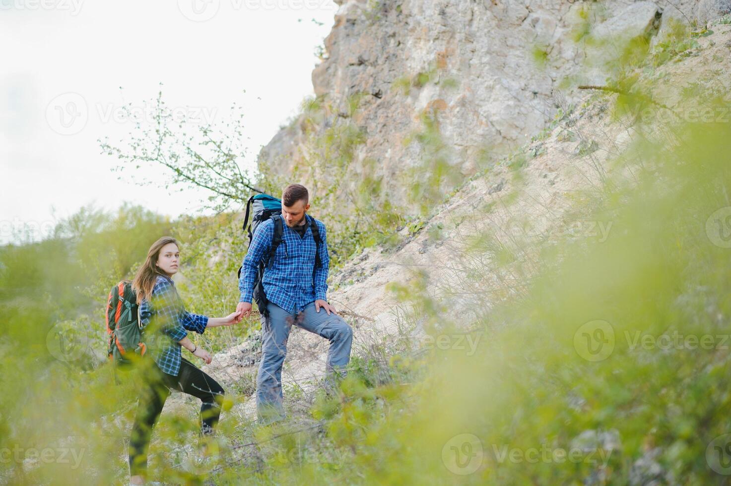wandelaar vent geeft een hand- naar de meisje terwijl wandelen in de bergen, helpen en vriendschap concept foto