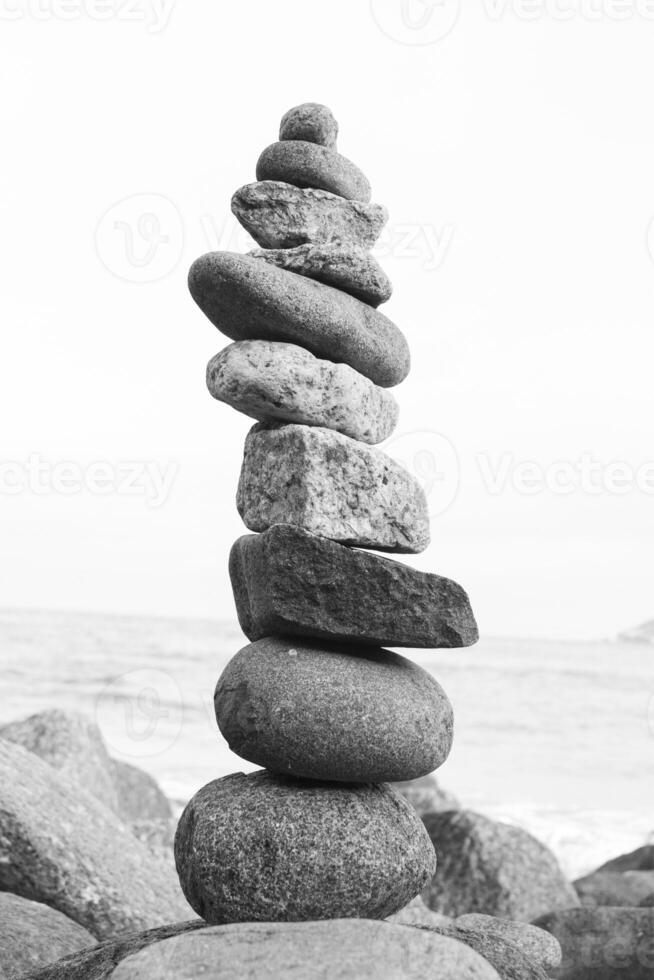 zwart en wit fotograaf van stapel van rotsen Aan de strand foto