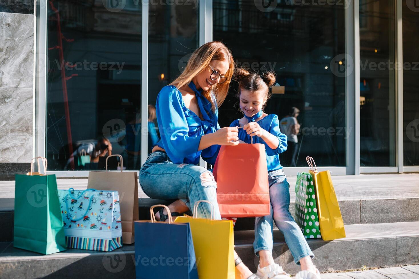 jong moeder en haar dochter aan het doen boodschappen doen samen. vrouw met meisje kind na boodschappen doen in straat. vrouw met dochter met boodschappen doen Tassen buitenshuis. vrouw en haar dochter na boodschappen doen foto