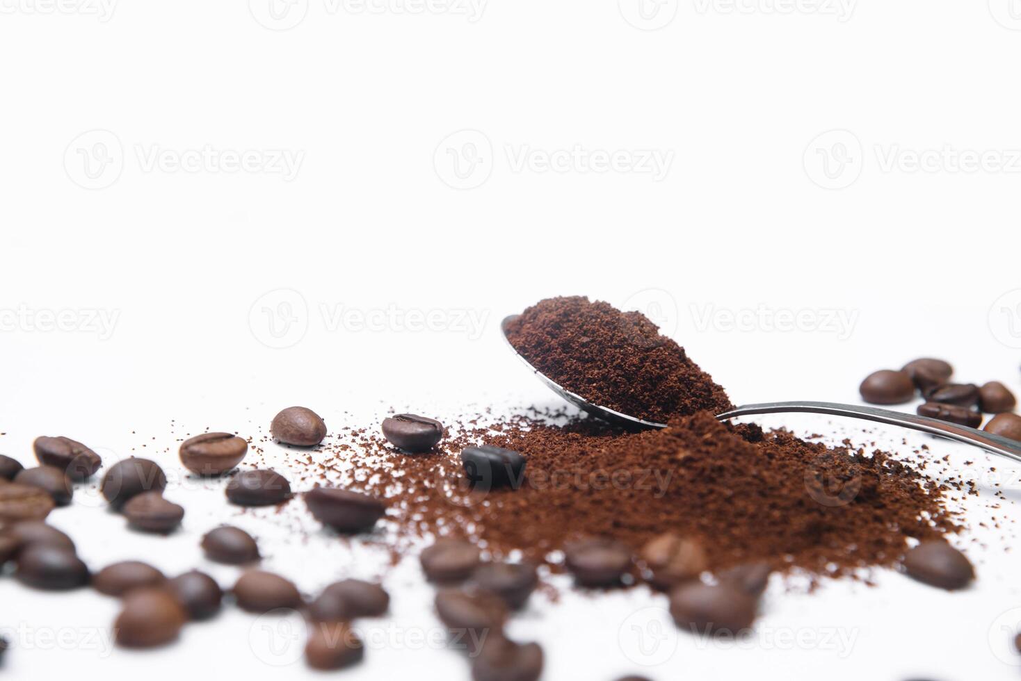 geaard koffie in een lepel omringd met bonen geïsoleerd foto