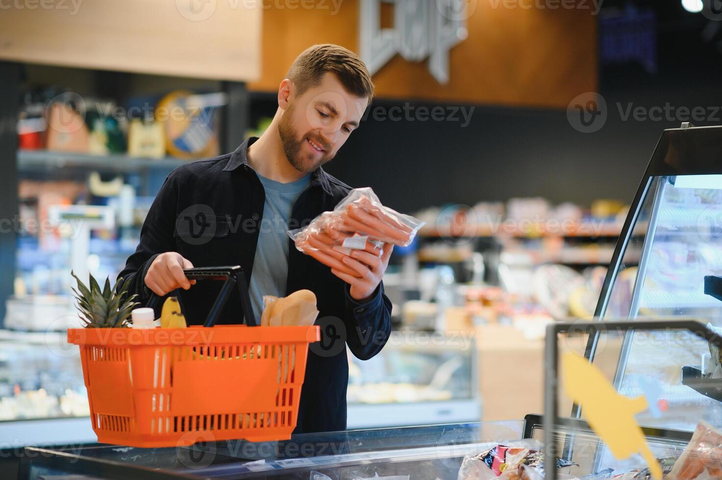 klant in supermarkt. Mens aan het doen kruidenier boodschappen doen staand met kar kiezen voedsel Product binnenshuis. vent buying boodschappen in voedsel op te slaan. selectief focus, kopiëren ruimte. foto