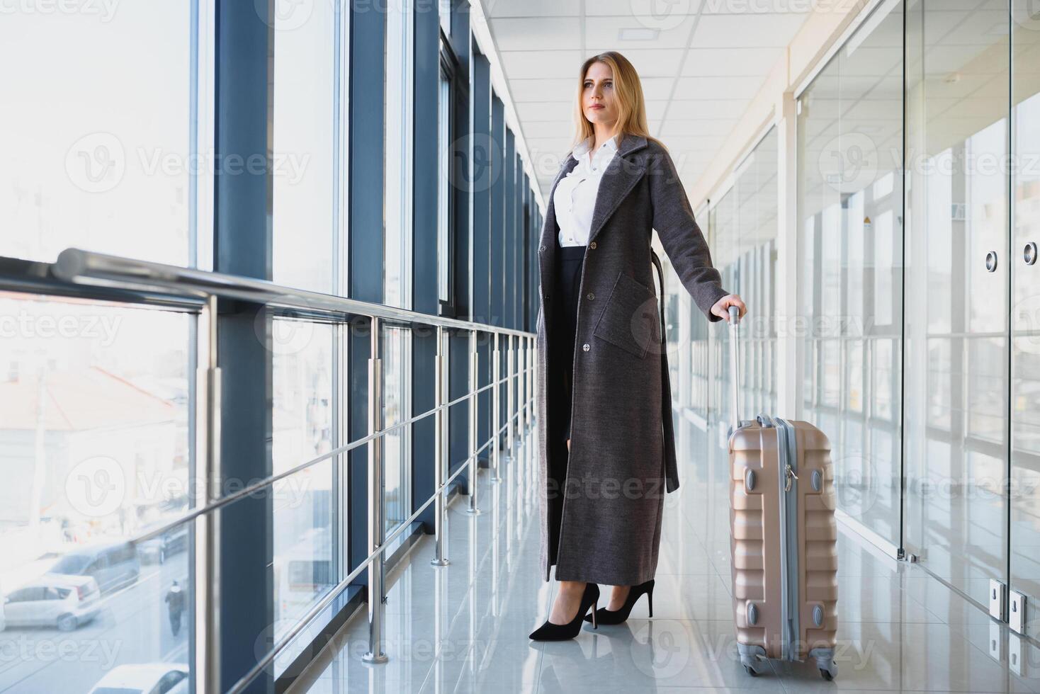 portret van geslaagd bedrijf vrouw op reis met geval Bij luchthaven. mooi elegant vrouw reizen met bagage. foto