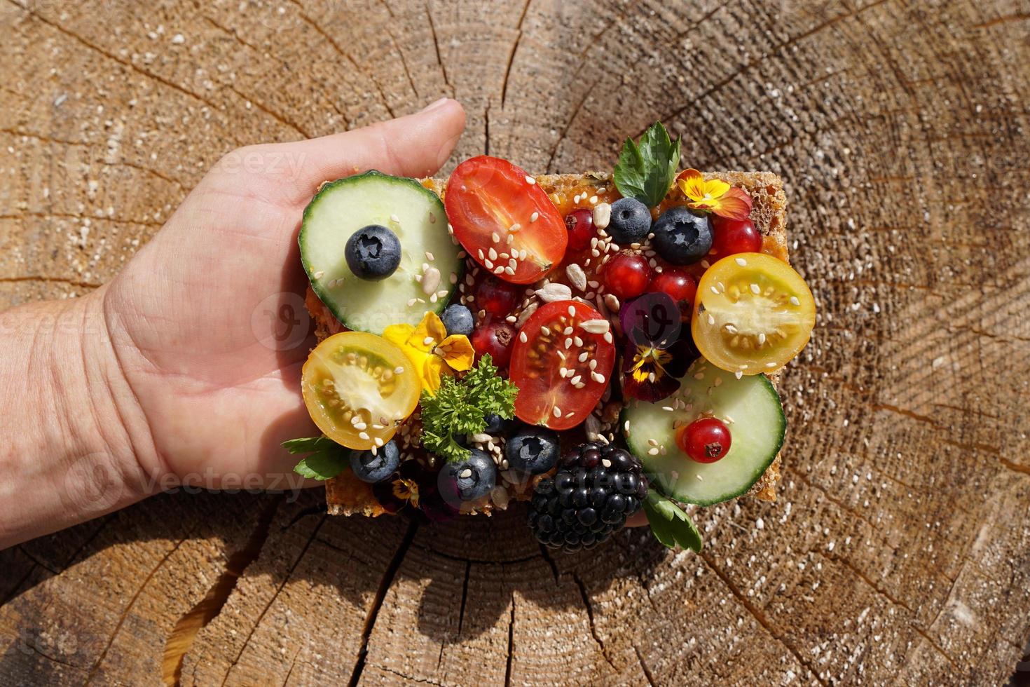 plakje gezond volkorenbrood zonder suiker met kleine komkommers, tomaten en bessen aan de kant van de vrouw. foto