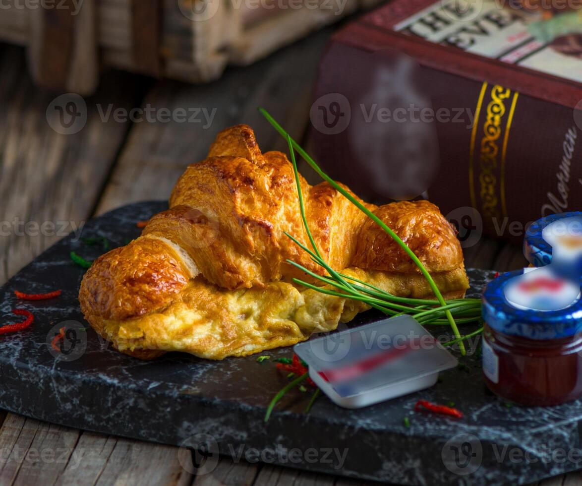 croissant omelet geserveerd in een schotel geïsoleerd Aan snijdend bord kant visie van ontbijt Aan houten achtergrond foto