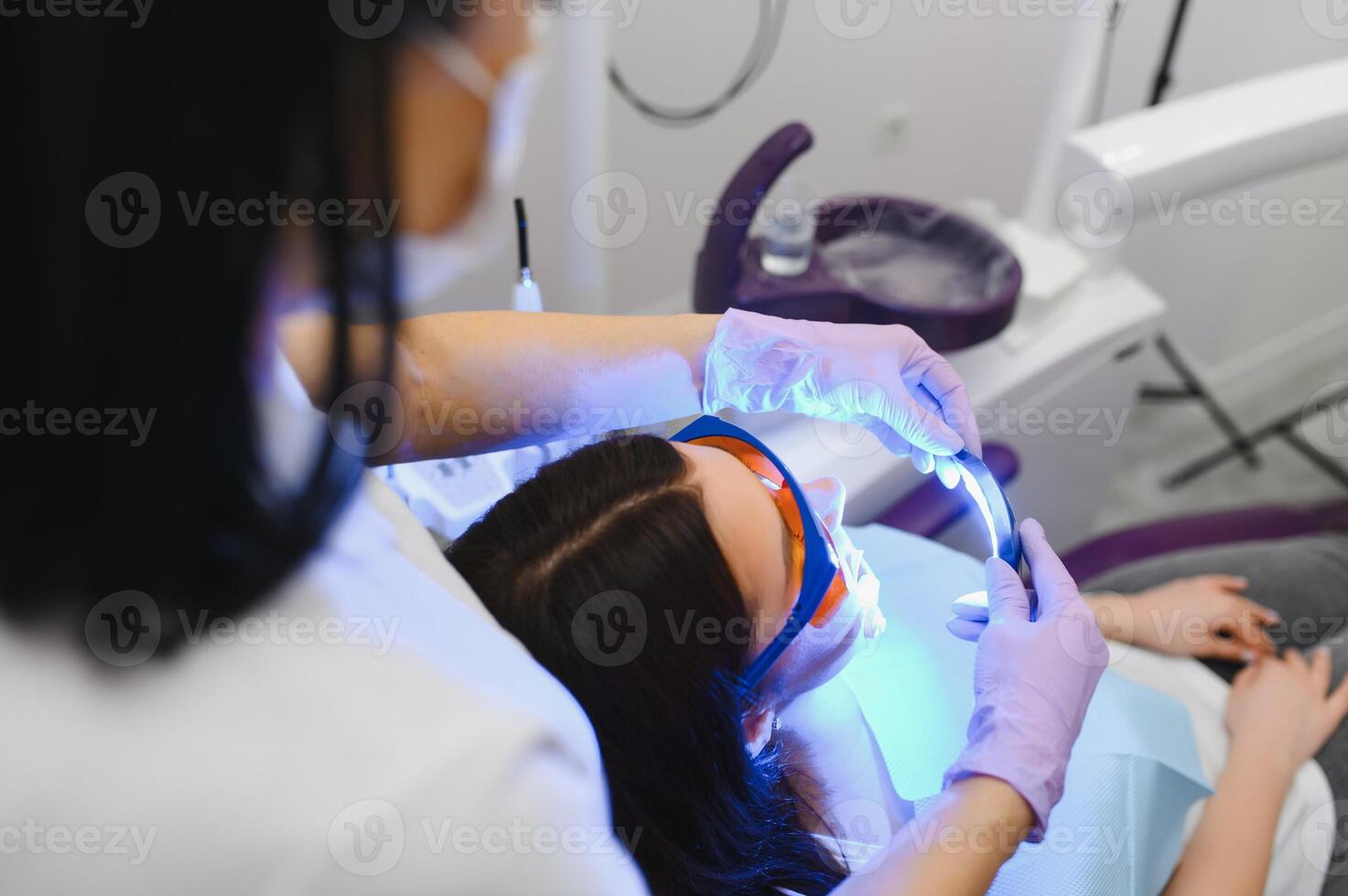 meisje geduldig in de tandheelkundig kliniek. tanden bleken uv lamp met fotopolymeer samenstelling. foto