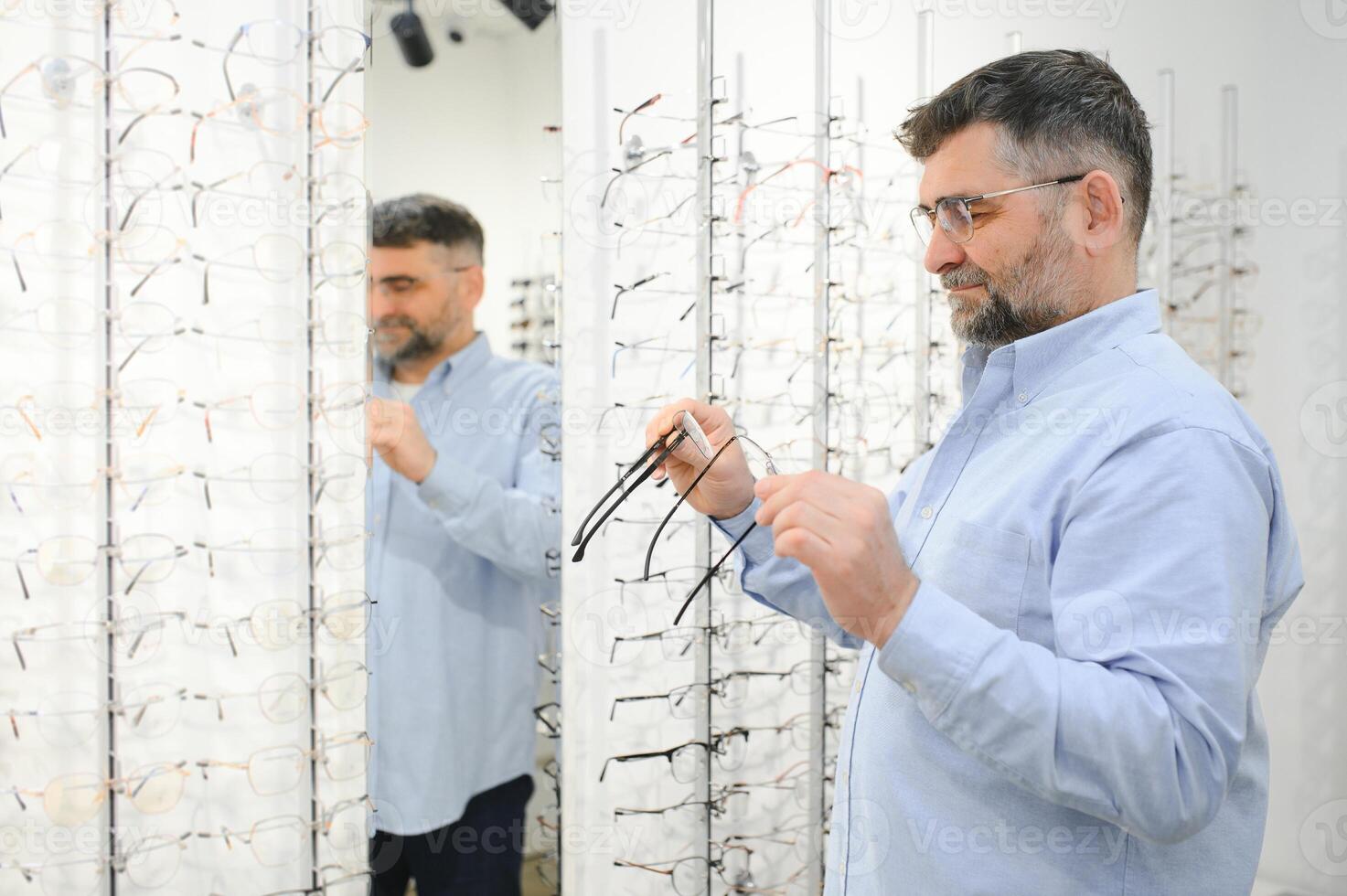 bril controleren, senior visie en ouderen Mens Bij een overleg plegen optometrie kliniek voor welzijn. Vrolijk, glimlach en oud gezicht met lens, kader en eyewear keuze in een op te slaan voor helpen krijgen een recept. foto