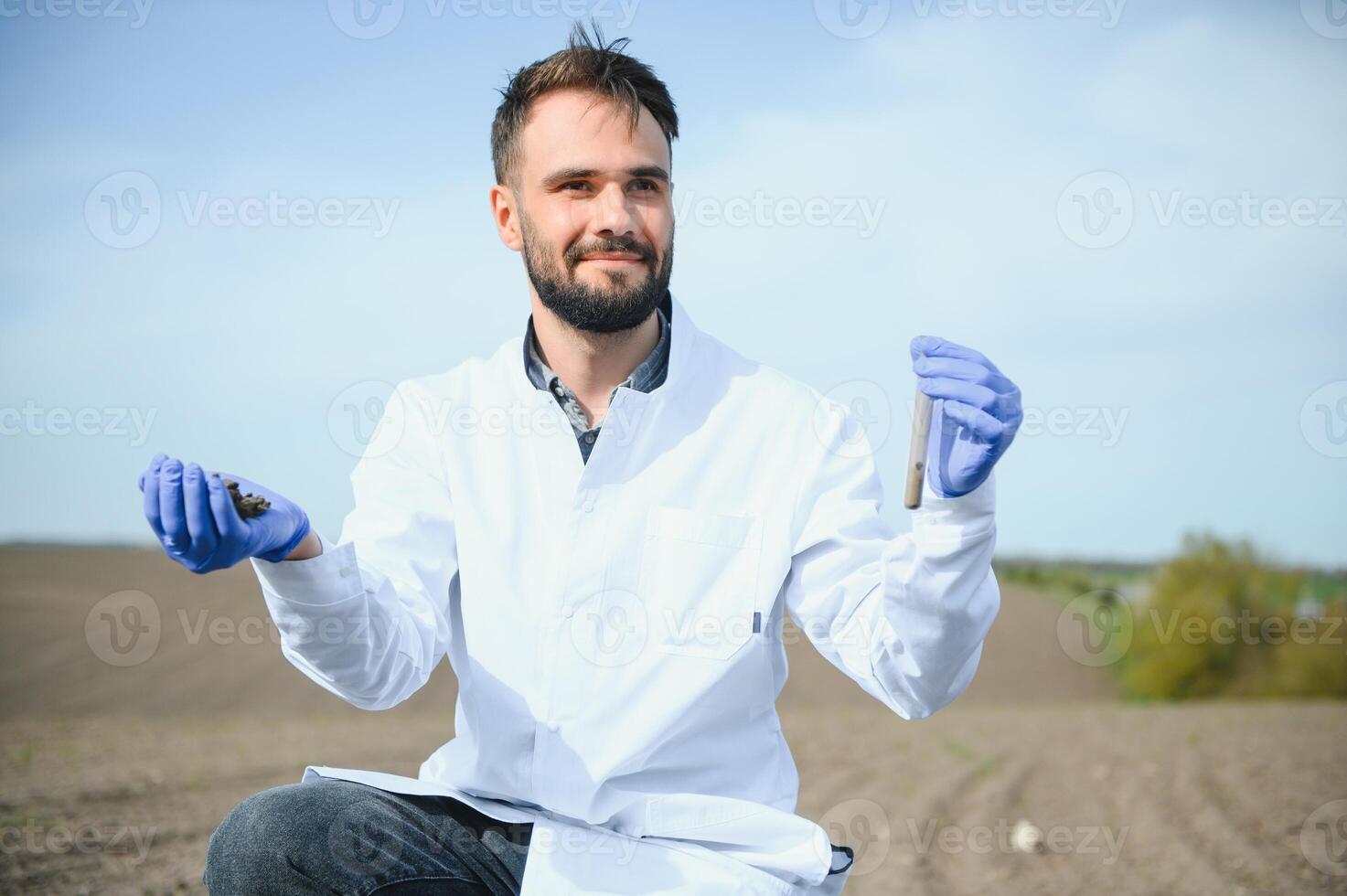 laboratorium arbeider Holding professioneel glaswerk en testen zwart bodem na oogst in de veld- foto