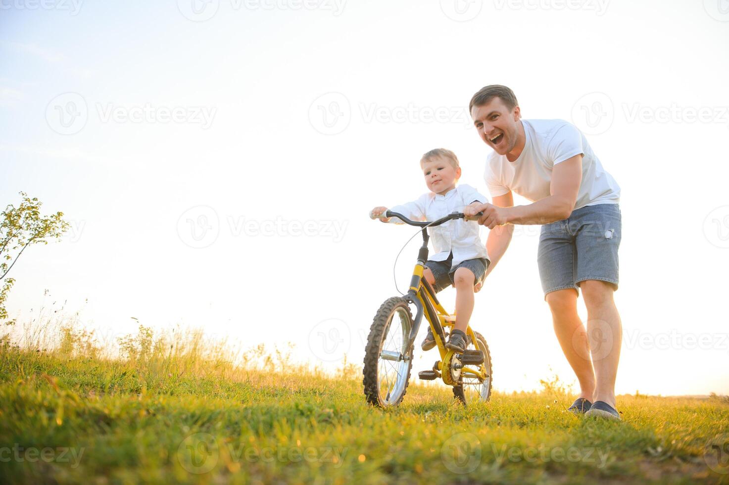 vader helpen zijn zoon rijden een fiets foto