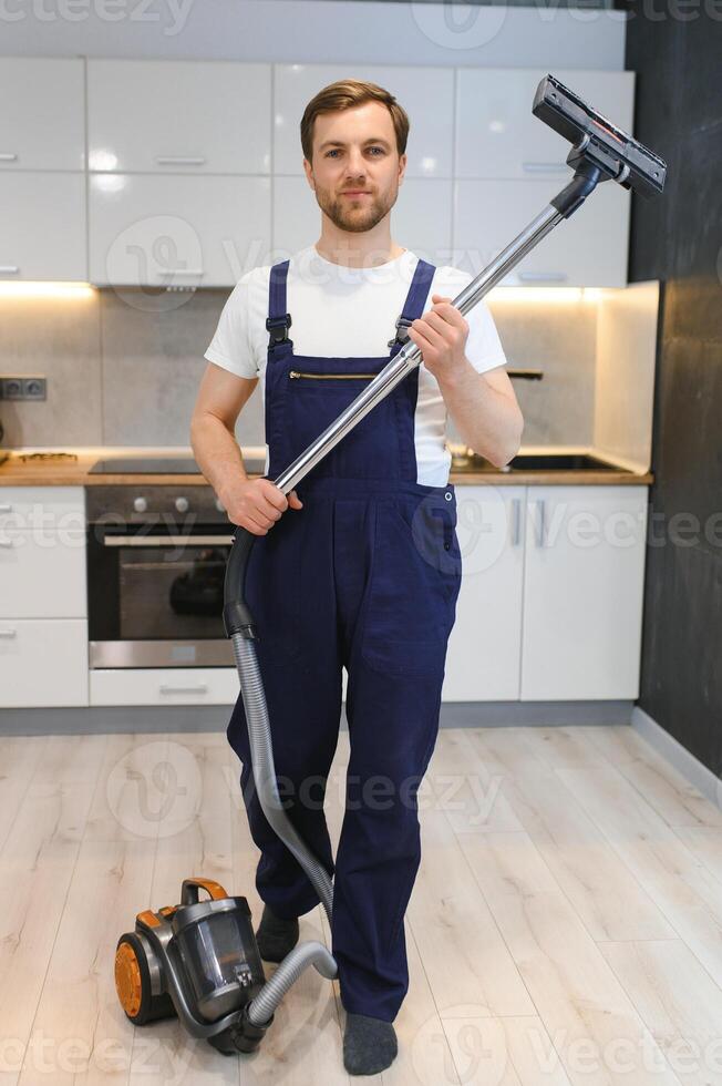 gelukkig mannetje conciërge schoonmaak tapijt met vacuüm schoonmaakster foto