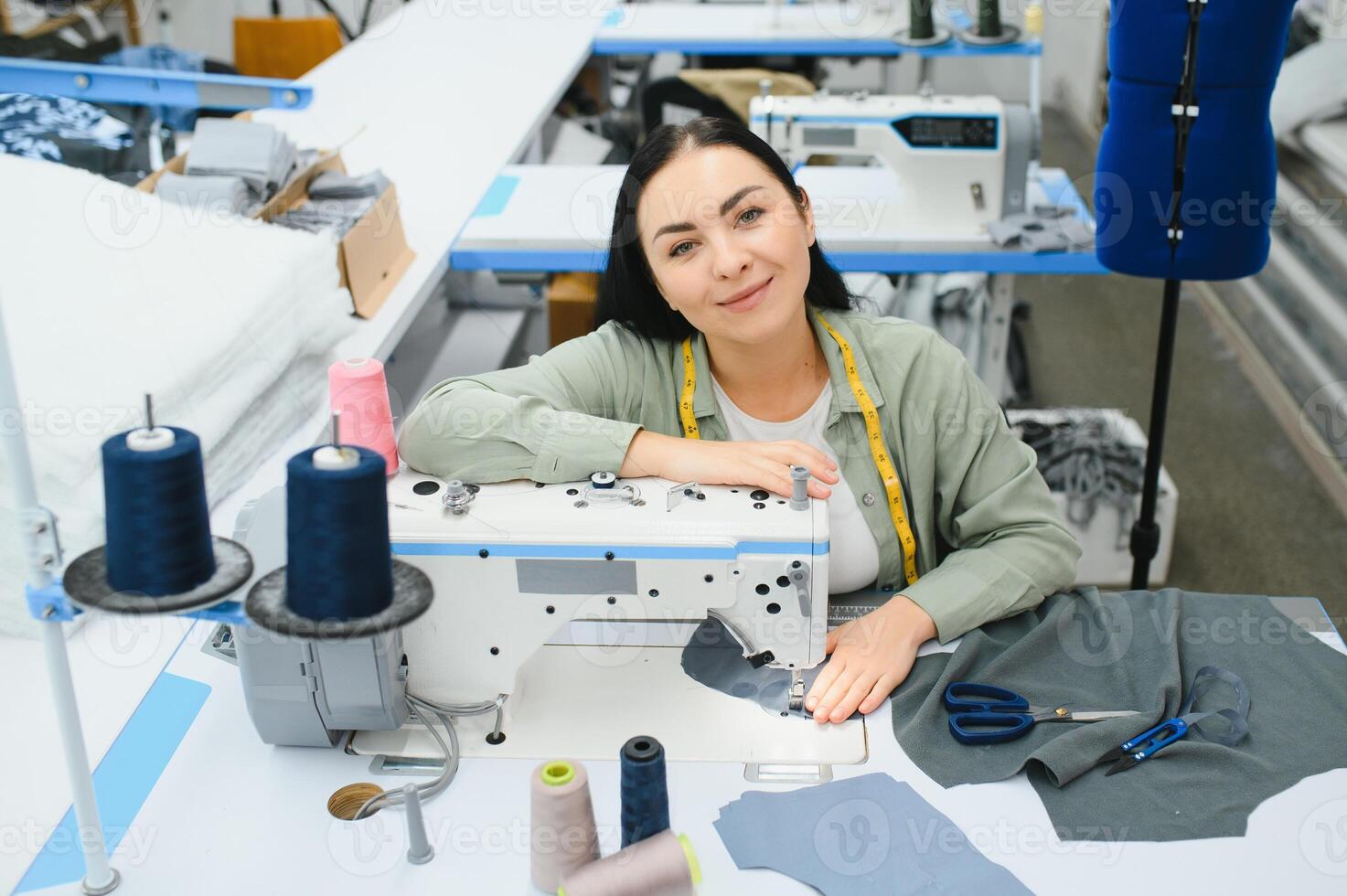 gelukkig vrouw naaister werken met naaien machine Bij textiel fabriek. foto