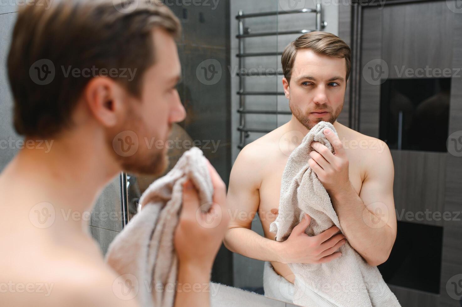 jong Mens op zoek in spiegel na scheren Bij huis foto