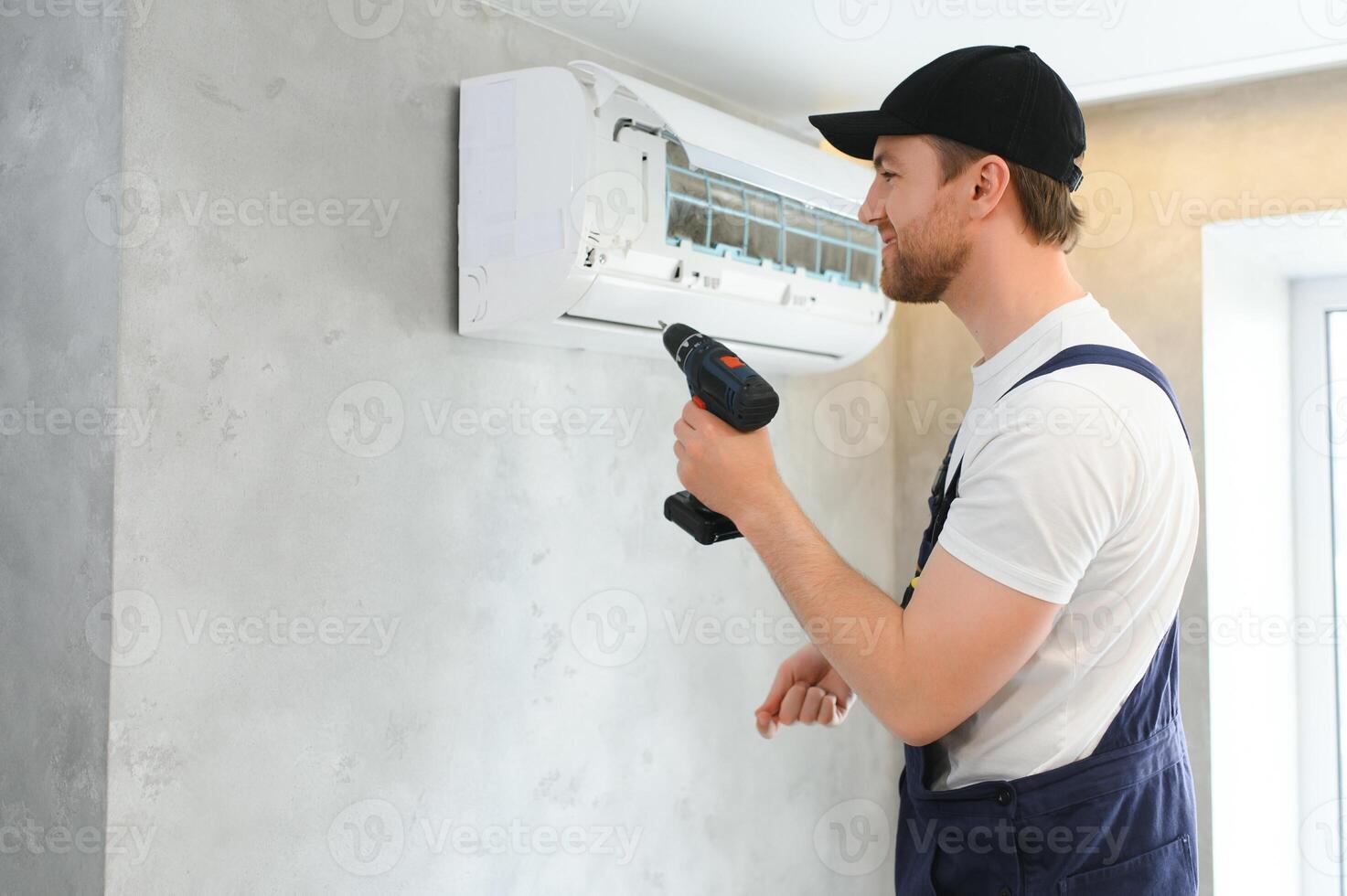 glimlachen jong mannetje elektricien reparatie conditioner in cliënt huis. Mens monteur of klusjesman fix filters in lucht staat apparaat Bij klant huis foto