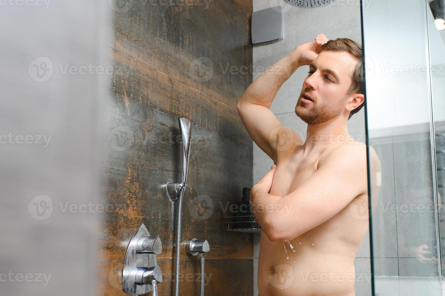 ontspannende na stressvol dag. taille omhoog portret van naakt gespierd heer nemen douche Bij huis. foto