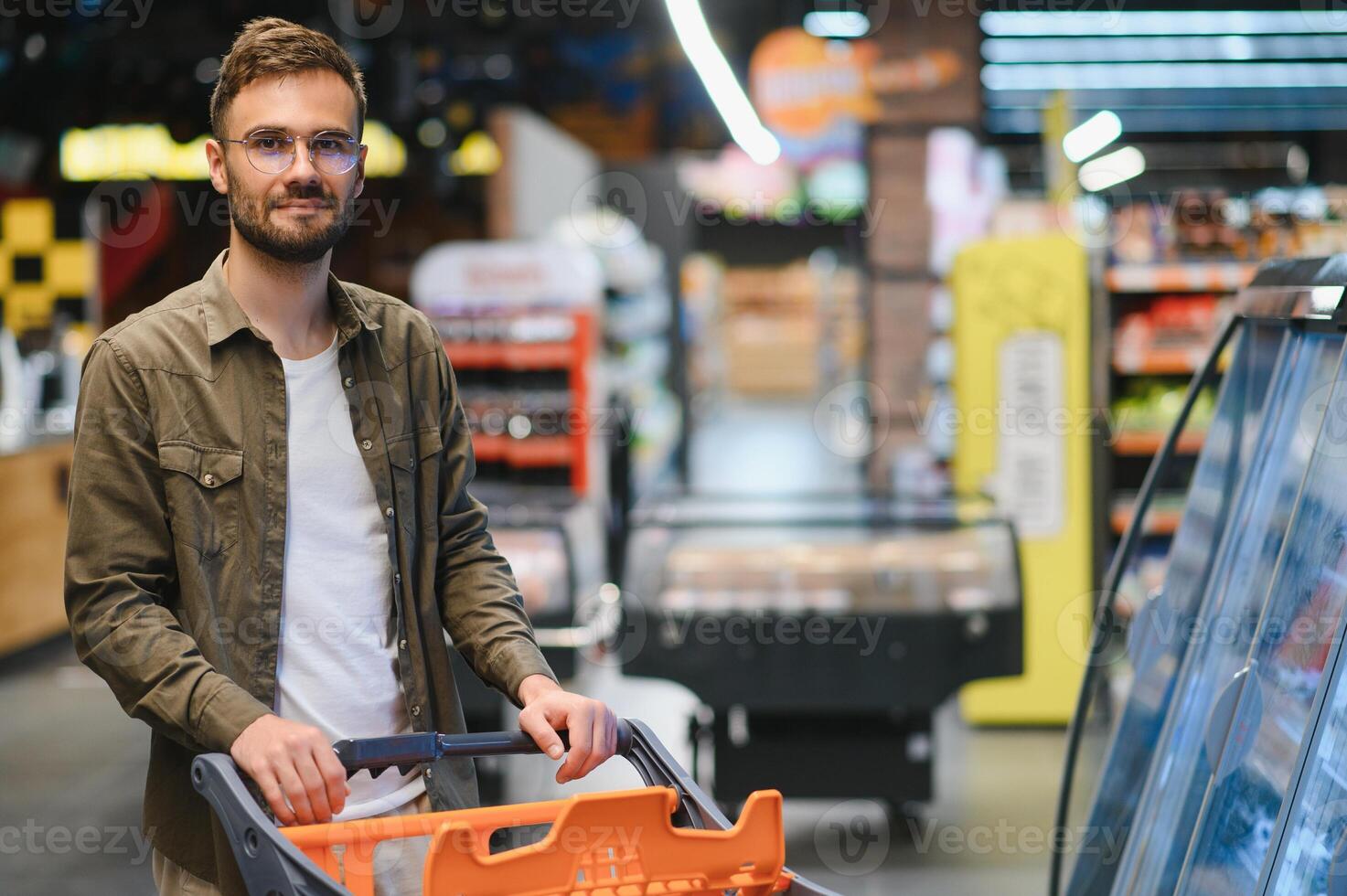 knap glimlachen Mens boodschappen doen in supermarkt voortvarend trolley foto