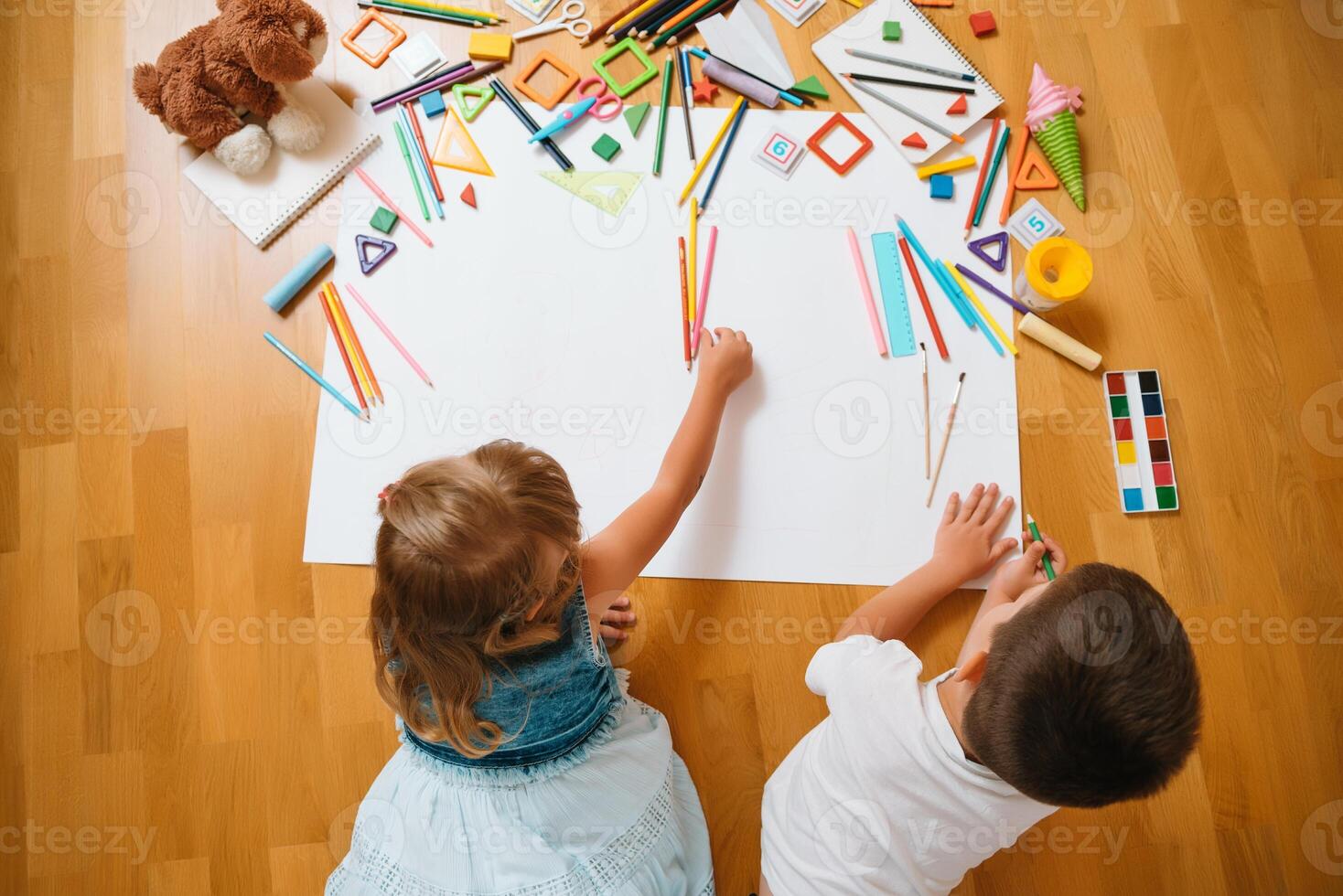 kinderen tekening Aan verdieping Aan papier. peuter- jongen en meisje Speel Aan verdieping met leerzaam speelgoed - blokken, trein, spoorweg, vlak. speelgoed voor peuter- en kleuterschool. kinderen Bij huis of kinderopvang. top visie. foto