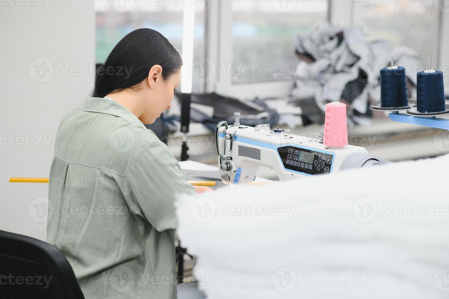 gelukkig vrouw naaister werken met naaien machine Bij textiel fabriek. foto
