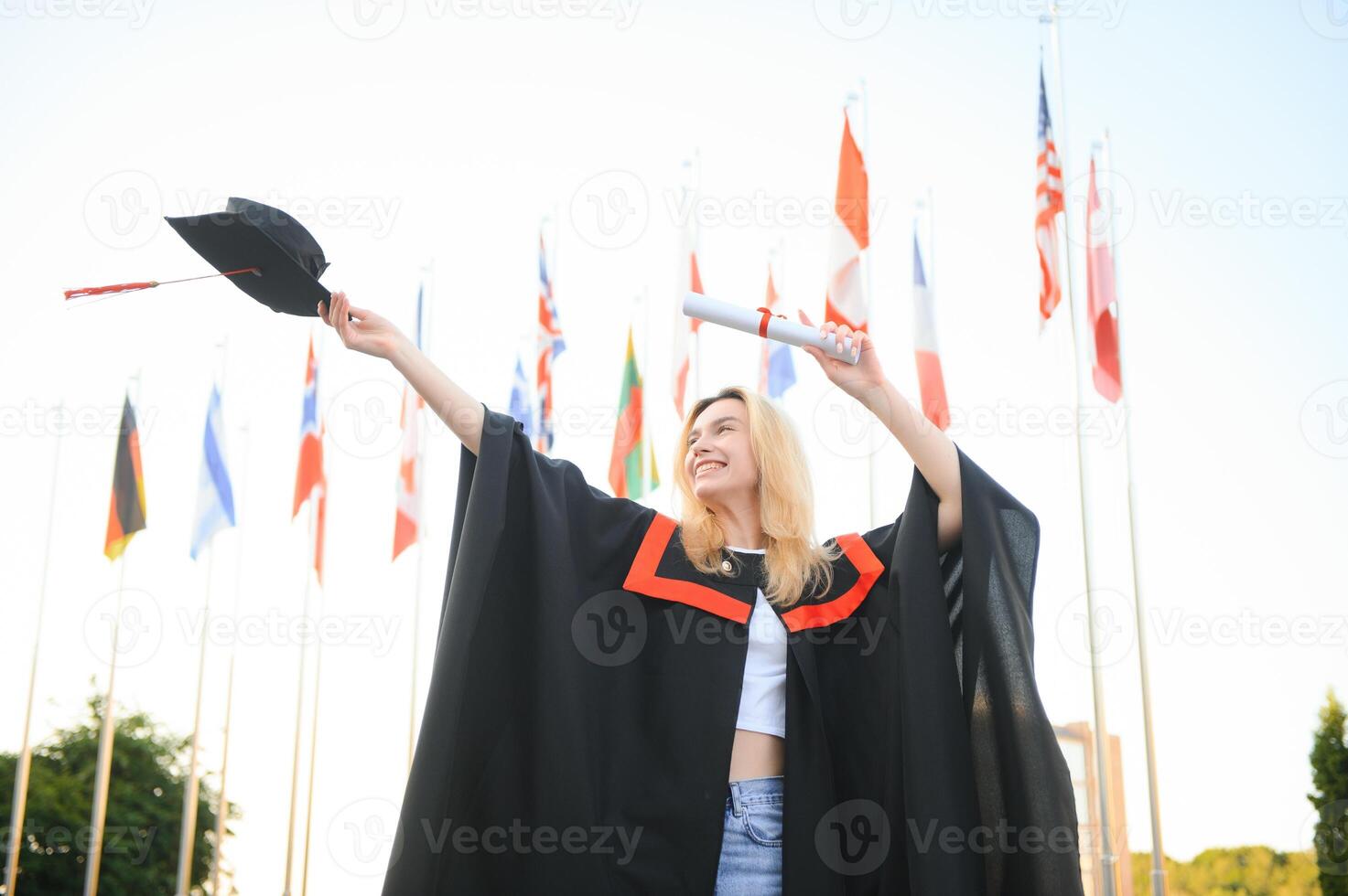 gelukkig Universiteit afstuderen meisje. de meisje is staand in de buurt de Universiteit tegen de achtergrond van de vlaggen van verschillend landen. de concept van Internationale onderwijs. foto