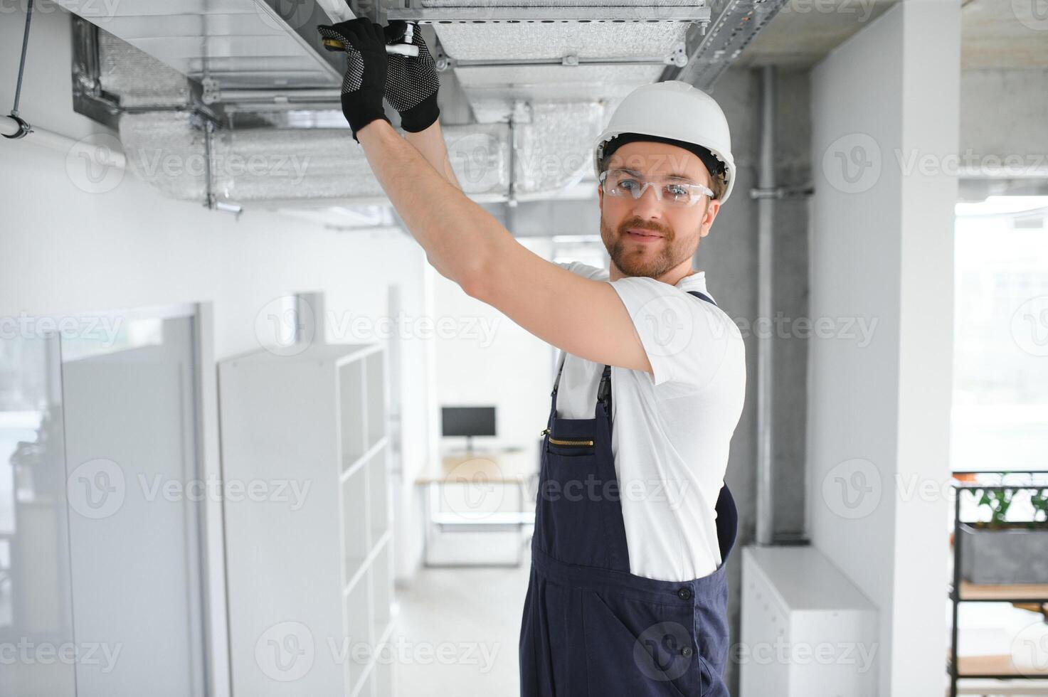 Kaukasisch hvac technicus arbeider in zijn Jaren 40 testen nieuw geïnstalleerd magazijn ventilatie systeem. reclame verwarming, koeling en lucht ventilatie systemen foto