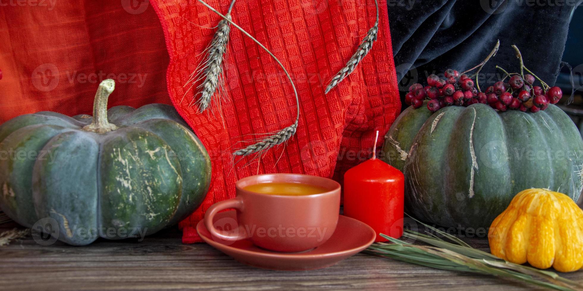 herfst stilleven. pompoenen, kaarsen, granen en een kopje op een houten tafel. foto