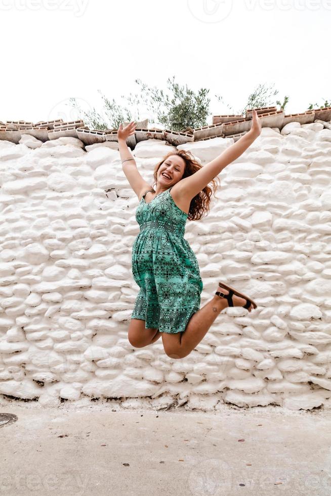 jonge vrouw springen en vieren op de achtergrond van oude bakstenen muur. foto