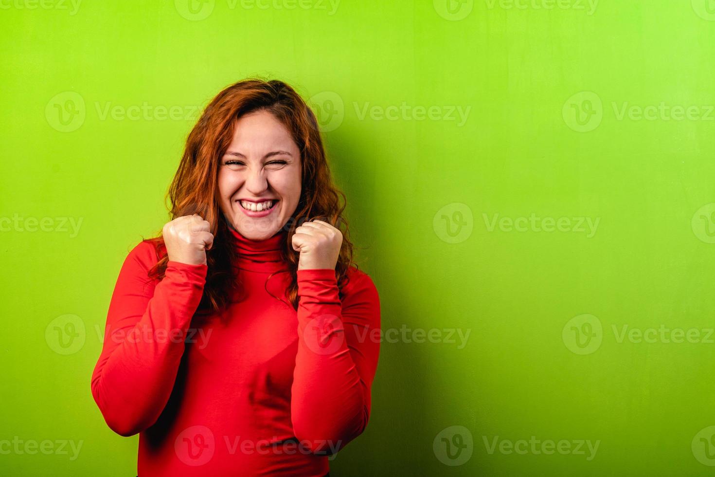 expressieve gelukkige roodharige vrouw op groene achtergrond en kopieer ruimte foto