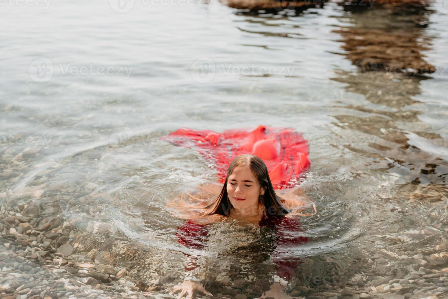 vrouw reizen zee. gelukkig toerist in rood jurk genieten nemen afbeelding buitenshuis voor herinneringen. vrouw reiziger poseren in zee strand, omringd door vulkanisch bergen, sharing reizen avontuur reis foto