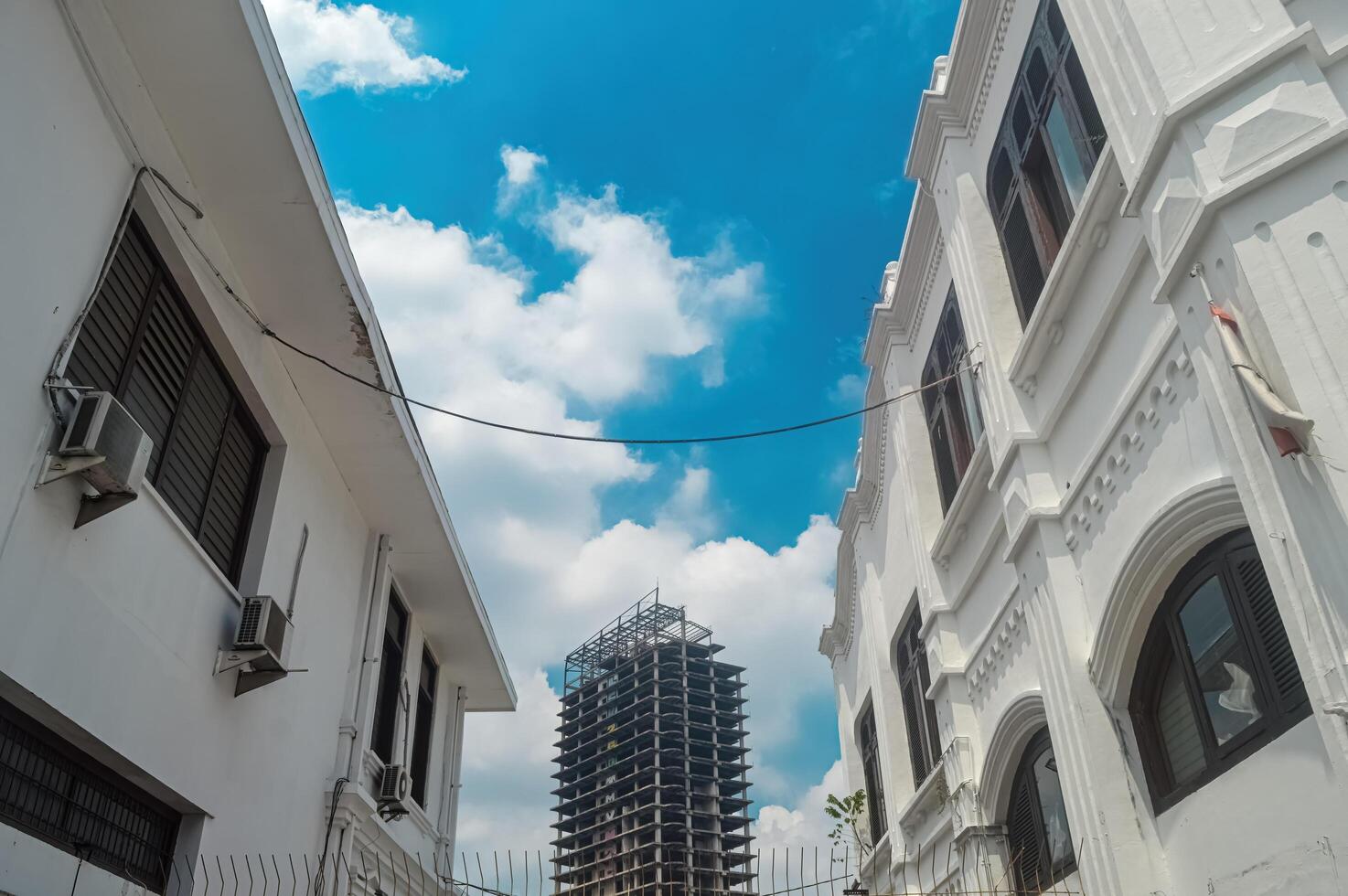 een onvoltooid en verlaten hoog stijgen toren gebouw met oude gebouw lijsten, Indonesië, 2 maart 2024. foto