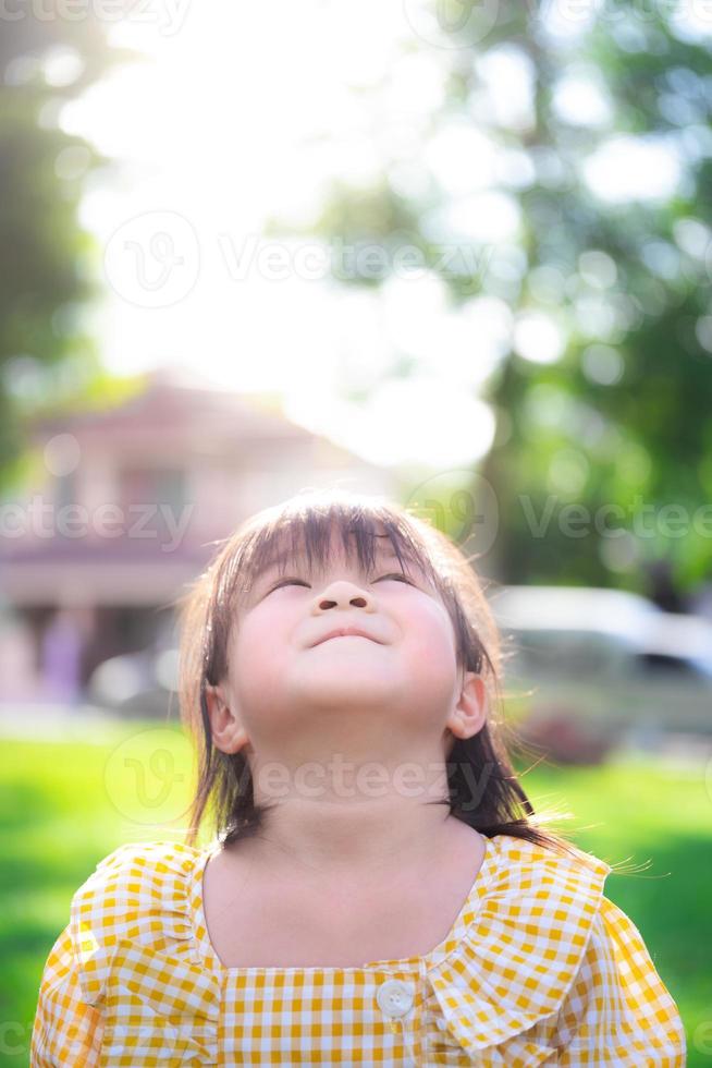 verticale foto's van heldere jonge meisjes die naar de lucht kijken. focus op de lachende lippen van het Aziatische meisje. kinderen dragen gele kleding, 5 jaar oud. foto