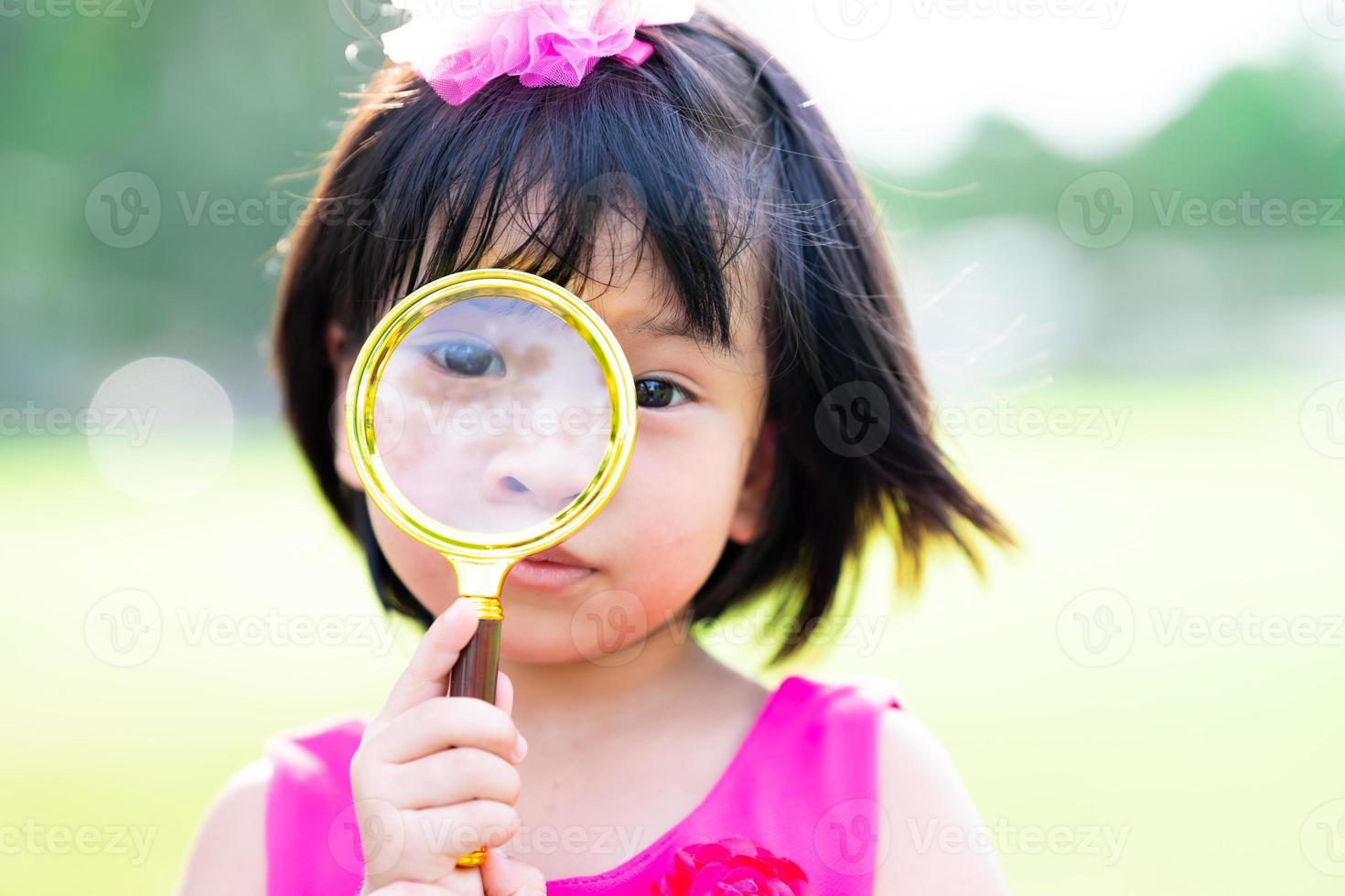 hoofdschot. schattig Aziatisch kindmeisje dat door een gouden verkoopbril kijkt. kind van 4-5 jaar oud. foto