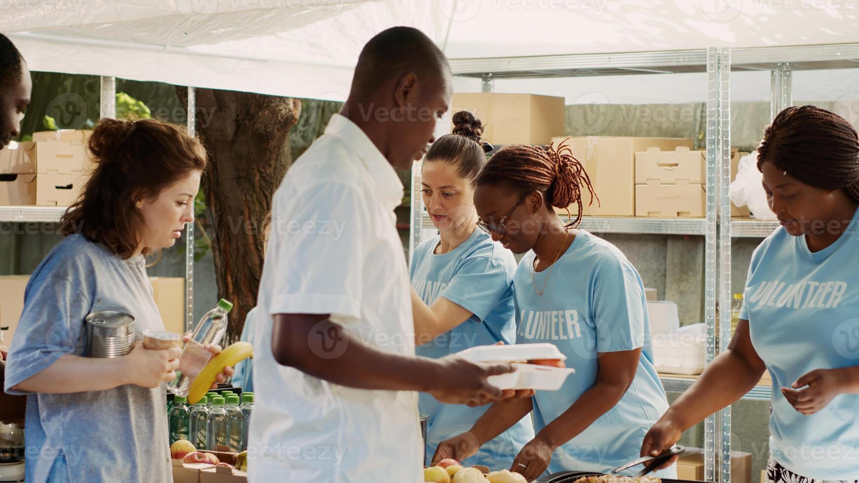 multiraciaal vrijwilliger Dames dienen maaltijden en niet bederfelijk producten naar hongerig en dakloos mensen. vriendelijk liefdadigheid arbeiders overhandigen uit vrij voedsel naar de arm en behoeftig. statief schot. foto
