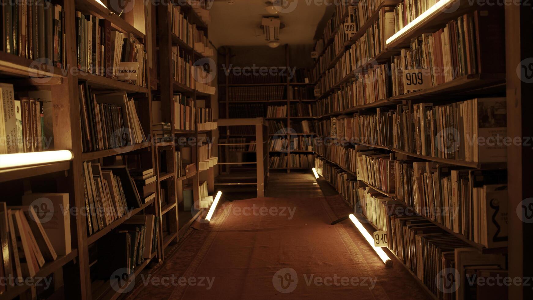 nacht bibliotheek met knippert lichten. voorraad filmmateriaal. gang met boekenkasten in nacht bibliotheek. knippert lichten in gangpad tussen boekenkasten van nacht bibliotheek foto