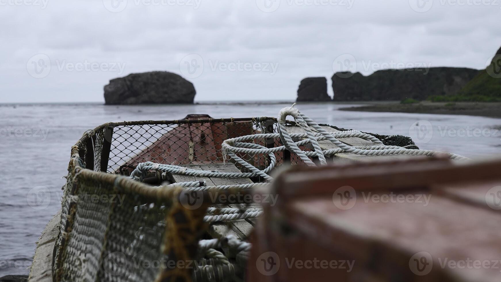 verlaten visvangst boot Aan achtergrond van rotsachtig kust. klem. visvangst boot met netto Aan kust met visie van rotsen. verlaten visvangst boot staat Aan kust van rotsachtig kust van zee foto