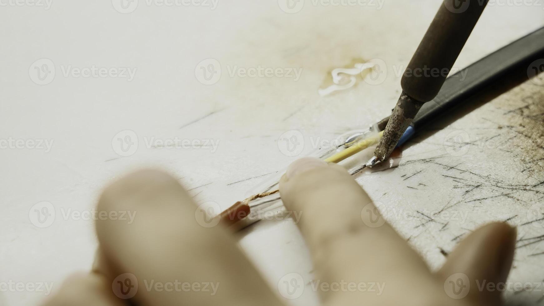 solderen ijzer, bedrading reparatie. creatief. dichtbij omhoog van industrieel achtergrond van arbeider in beschermend handschoenen repareren een draad. foto