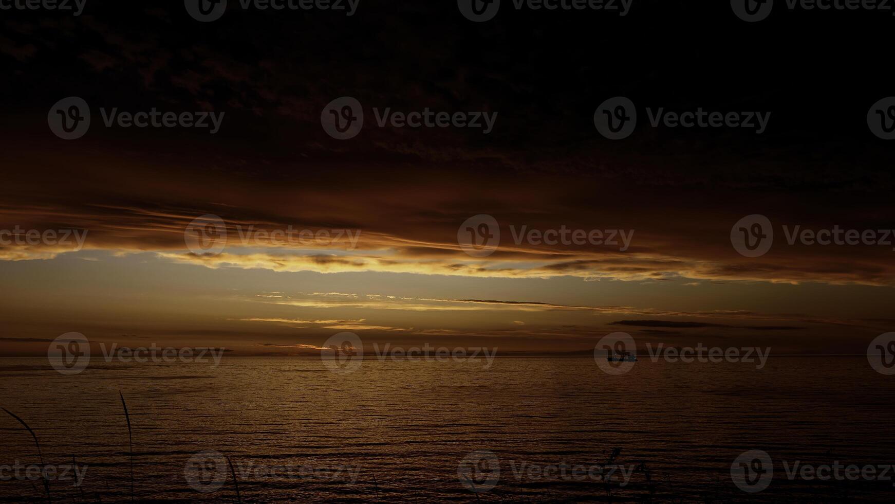 sprookje adembenemend zonsondergang bovenstaand kabbelend rivier- met een drijvend boot. klem. donker rood en oranje lucht, zwaar wolken bovenstaand water. foto