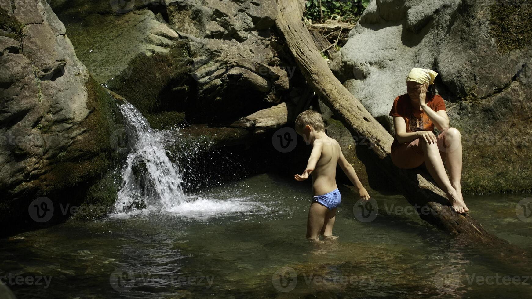 mam met jongen kind in tropisch waterval. creatief. familie van wandelaars Aan een zomer reis in oerwouden. foto