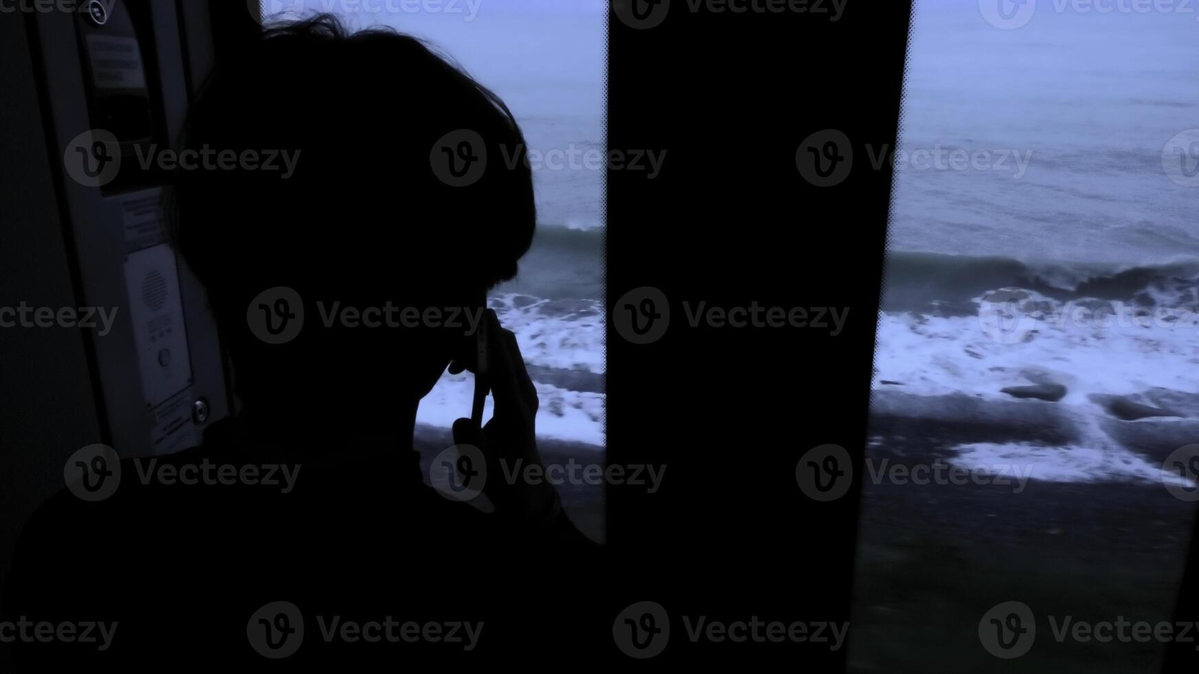 jong Mens staand De volgende naar een trein venster en op zoek buiten voorraad klem. Mens met smartphone op zoek door de venster Aan zee. foto