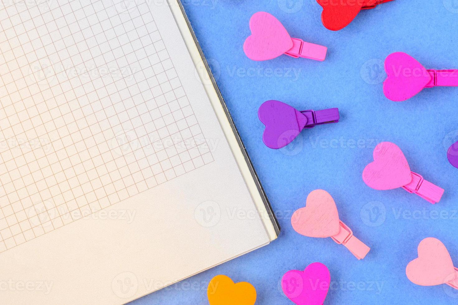 wit papier en kleine gekleurde hartjes op een blauwe achtergrond. conceptnotities voor Valentijnsdag foto