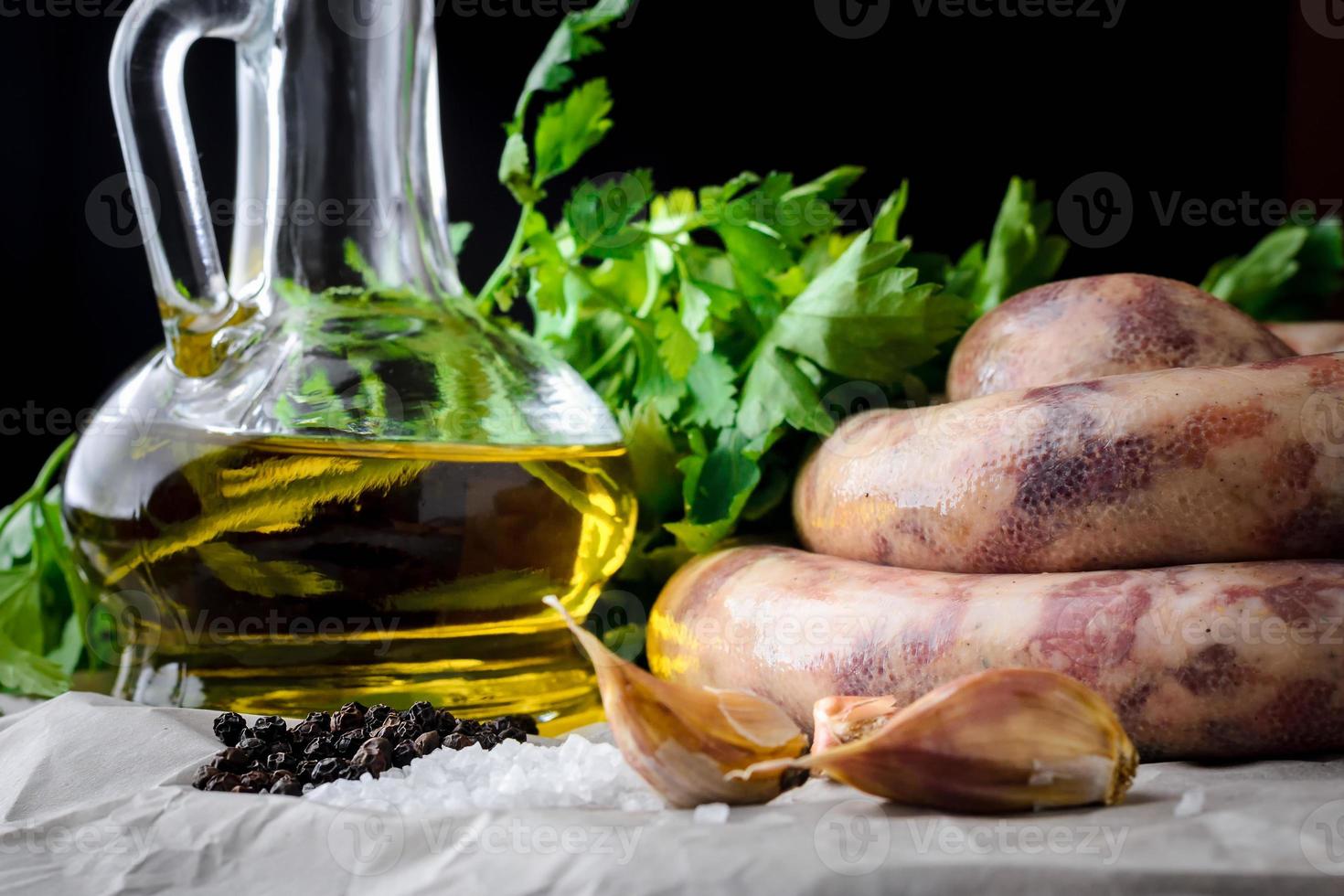 worstjes van vlees, kruiden en olijfolie op een donkere achtergrond foto