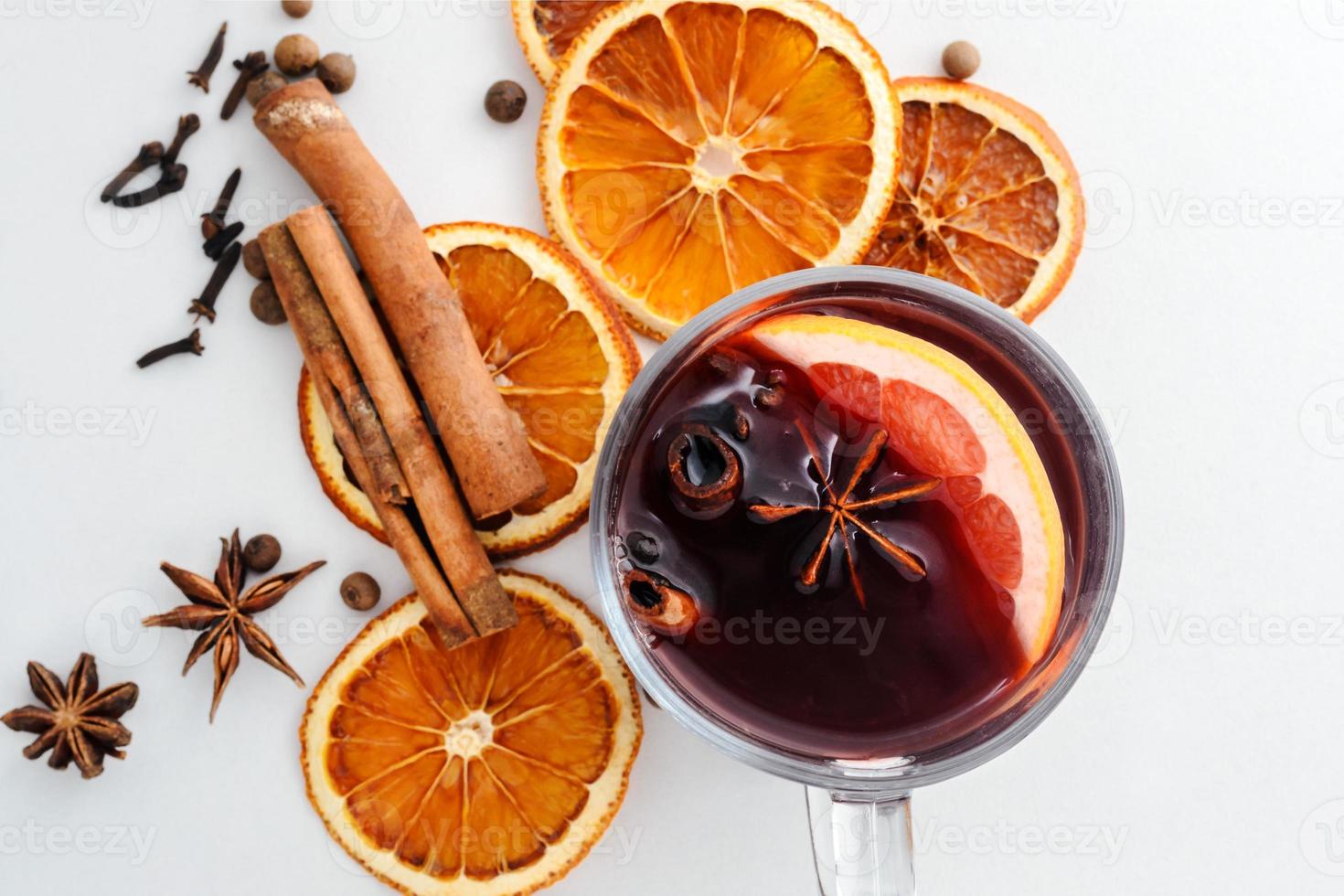 Glühwein in een glazen mok, gedroogde sinaasappelen en kruiden op een witte achtergrond foto