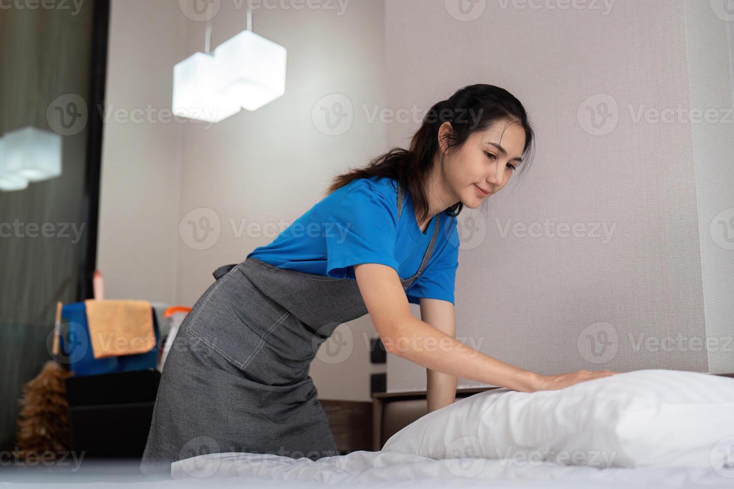 een vrouw Aziatisch personeel schoonmaak onderhoud, gereedschap en emmer voor werk. een jong vrouw schoonmaakster met producten naar schoon een slaapkamer foto