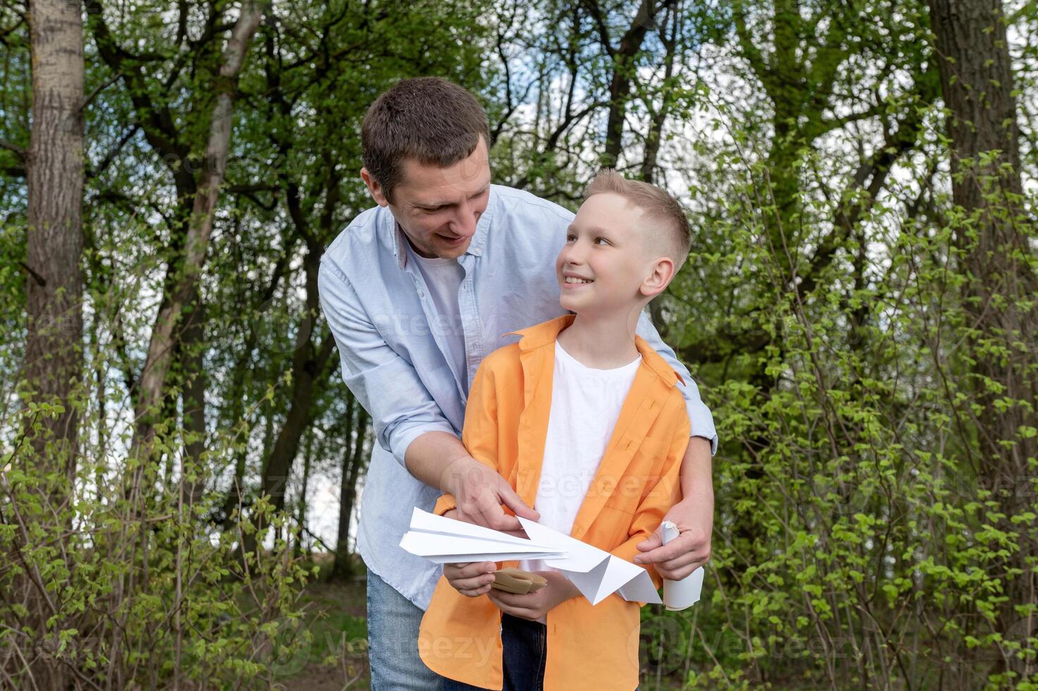 een gelukkig kind looks Bij zijn pa, wie houdt papier vliegtuigen in zijn handen. foto