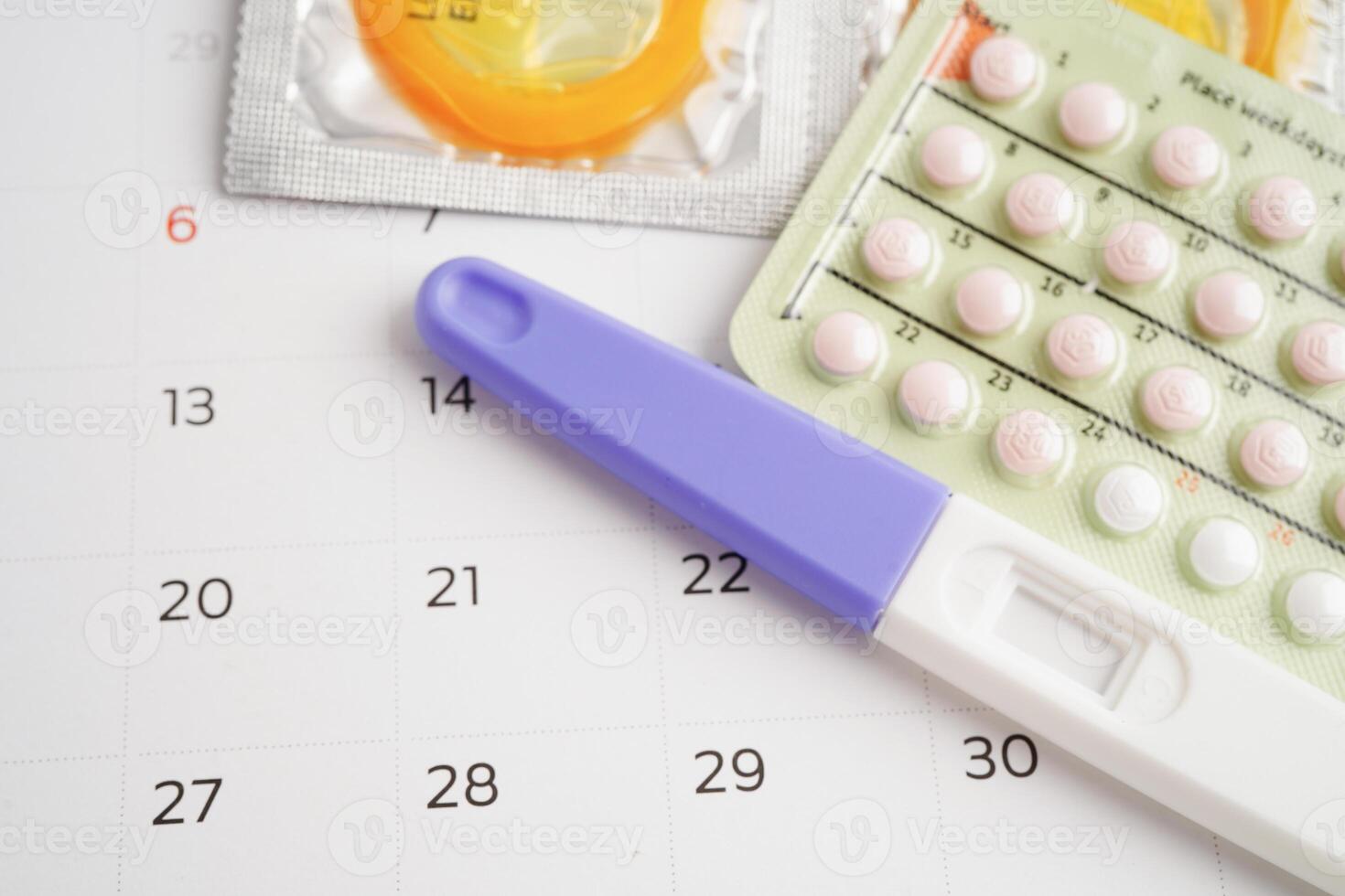 zwangerschap test met geboorte controle pillen en condoom voor vrouw Aan kalender, ovulatie dag. foto